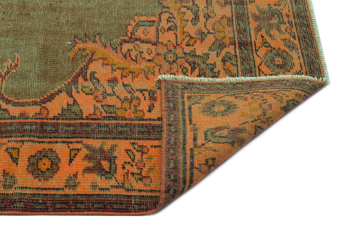 Olive green and orange traditional rug with a folded corner revealing a detailed floral medallion pattern.