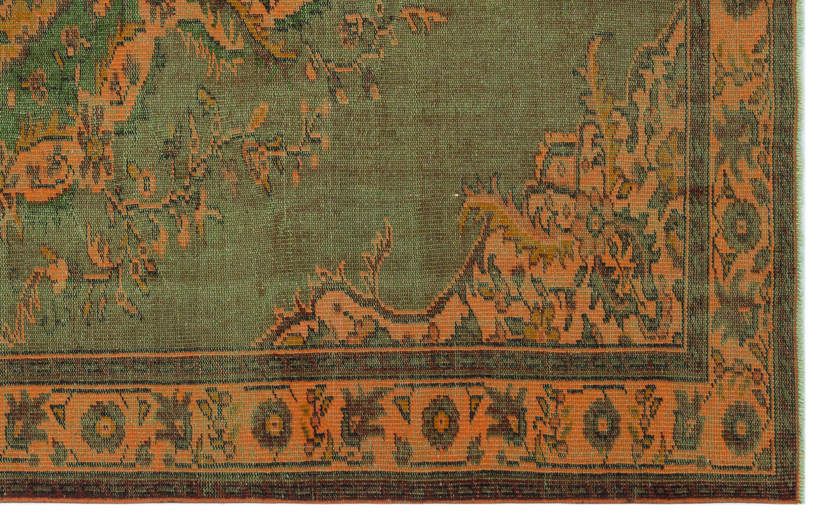 Olive green and burnt orange traditional rug with a distressed floral medallion pattern and a geometric border.