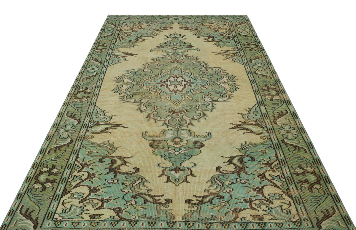 Sage green and beige vintage-style rug with a central floral medallion and ornate border on a white background.