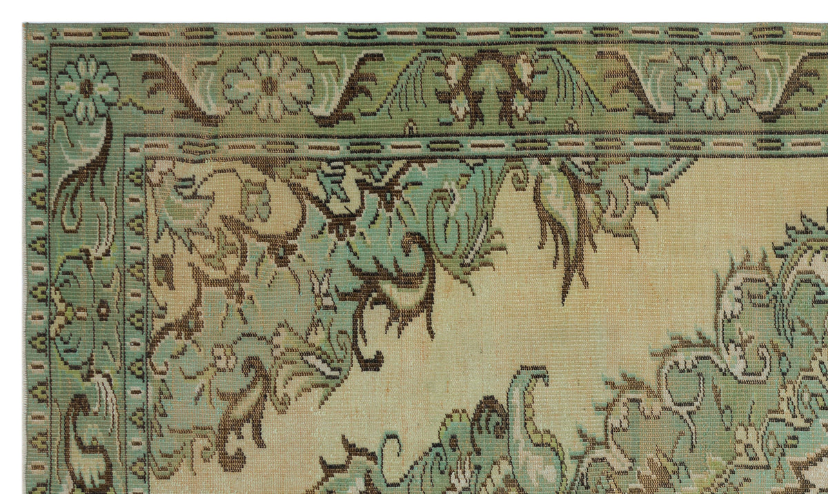 Sage green and beige rug with a traditional floral border and intricate vine-like patterns.