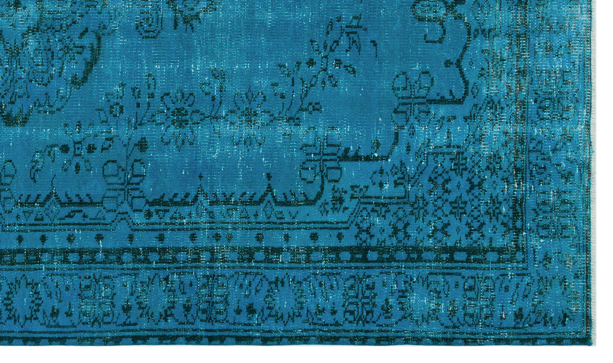 Bright turquoise rug with a distressed black floral and geometric border pattern.
