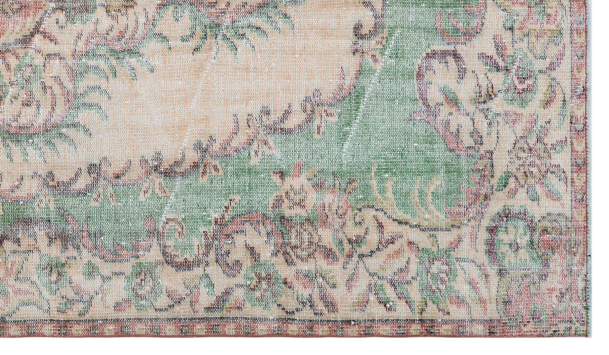 Distressed vintage-style rug with a faded floral medallion pattern in sage green, cream, and muted red.