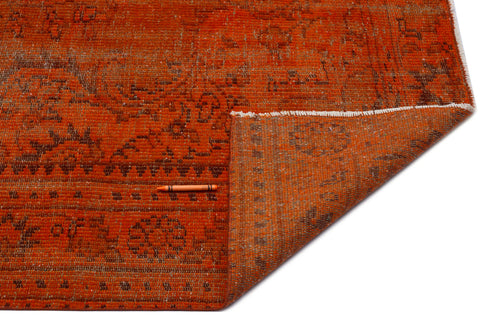 Load image 1 in gallery view. Burnt orange distressed rug with a faded brown traditional pattern and a folded corner, isolated on a white background.