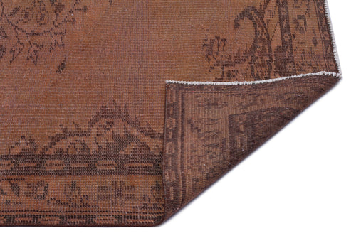 Load image 1 in gallery view. Rust-colored rug with a dark brown distressed floral pattern and a folded corner showing the reverse side.