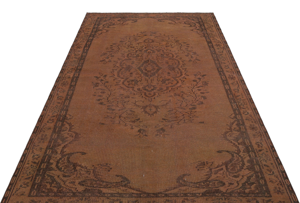 Distressed brown rug with a dark brown central floral medallion and a decorative border on a white background.