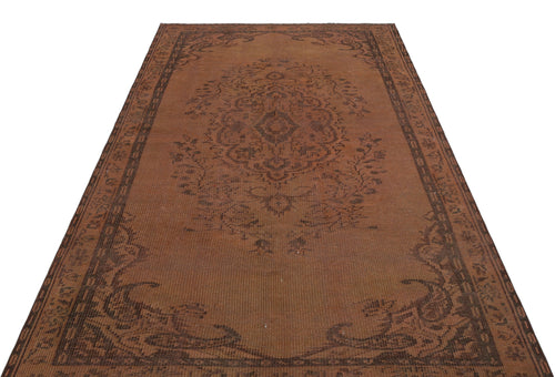 Load image 1 in gallery view. Distressed brown rug with a dark brown central floral medallion and a decorative border on a white background.