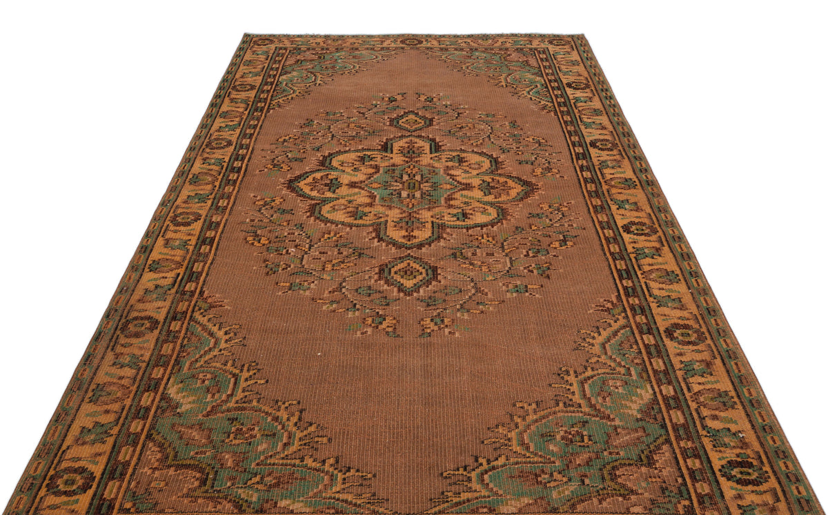 Brown traditional rug with a central floral medallion and ornate geometric border in green and tan accents.