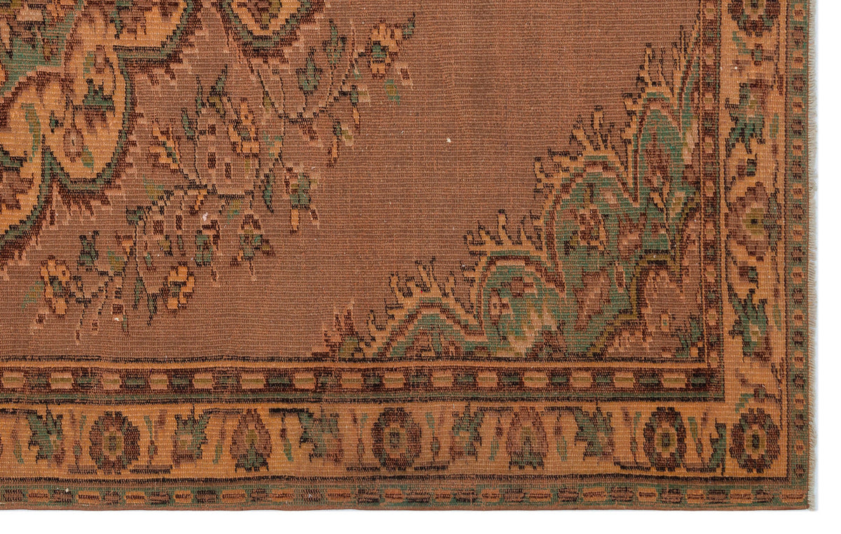 Brown traditional rug with green and tan floral motifs and a geometric border pattern.