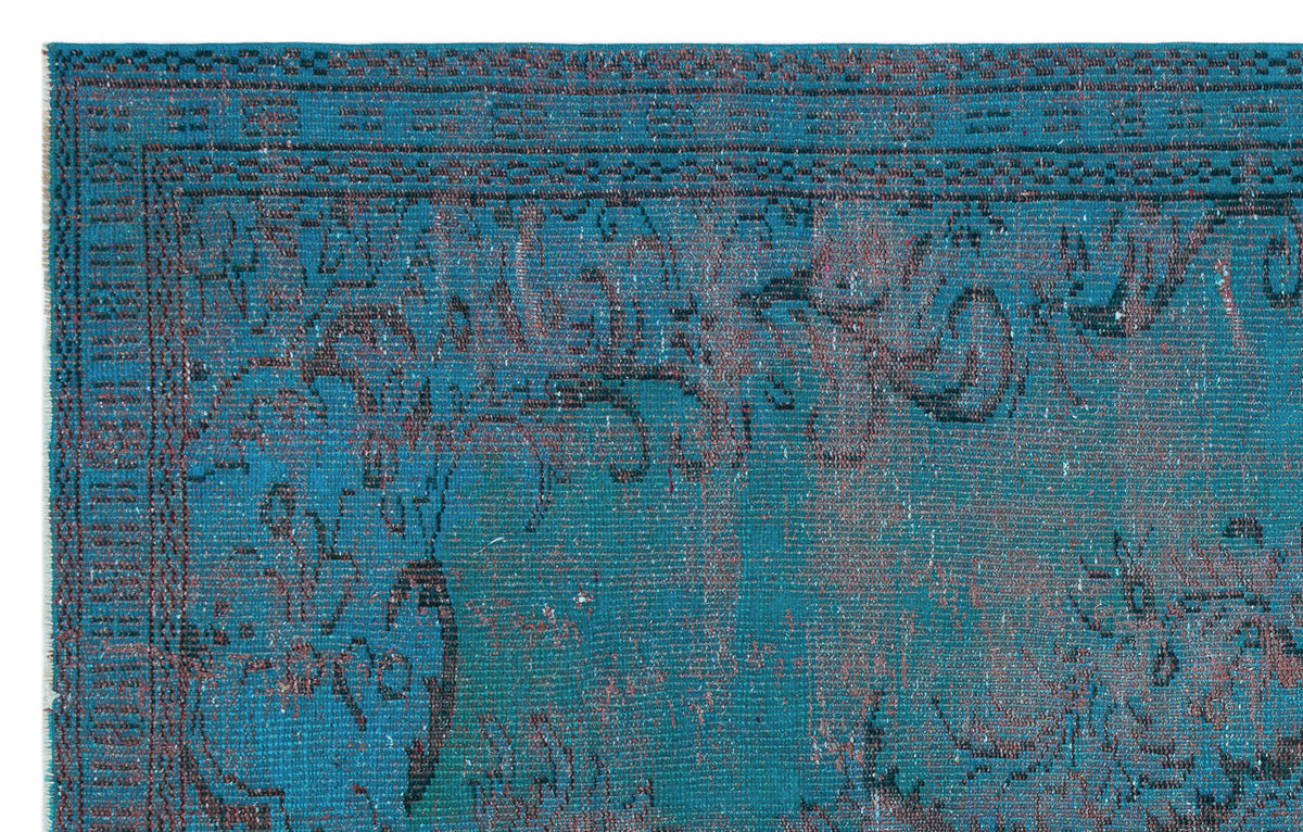 Teal and dark blue distressed rug with a faded traditional floral border and medallion pattern.