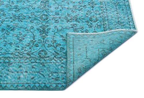 Load image 1 in gallery view. Turquoise rug with a dark grey floral pattern and a folded corner revealing the woven backing.