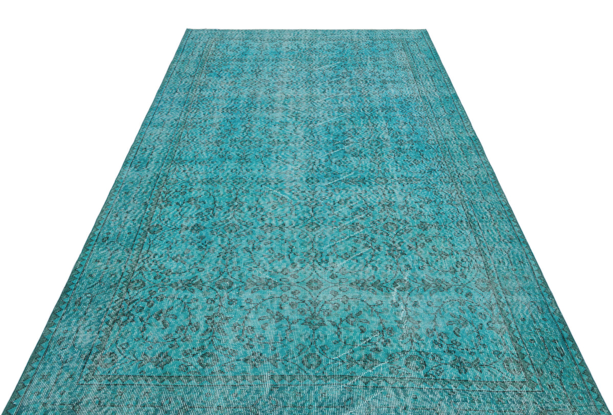 Turquoise vintage-style rug with a distressed floral medallion pattern and a bordered edge on a white background.