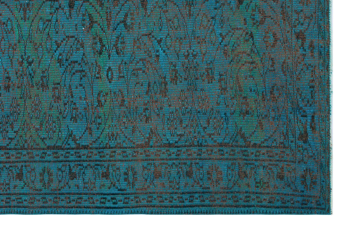 Teal and black rug with a distressed traditional floral medallion pattern and a geometric border.