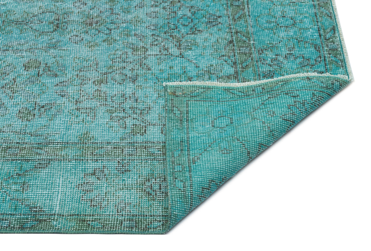 Teal and dark green distressed traditional rug with a folded corner, isolated on a white background.