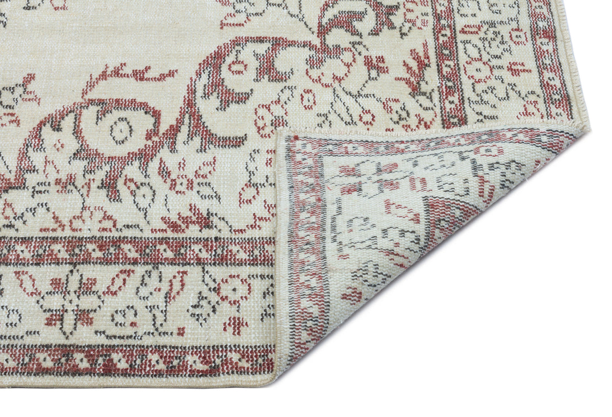Cream rug with a red and charcoal floral medallion pattern, shown with a corner folded to reveal the underside.