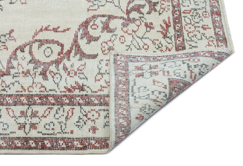 Load image 1 in gallery view. Cream rug with a red and charcoal floral medallion pattern, shown with a corner folded to reveal the underside.