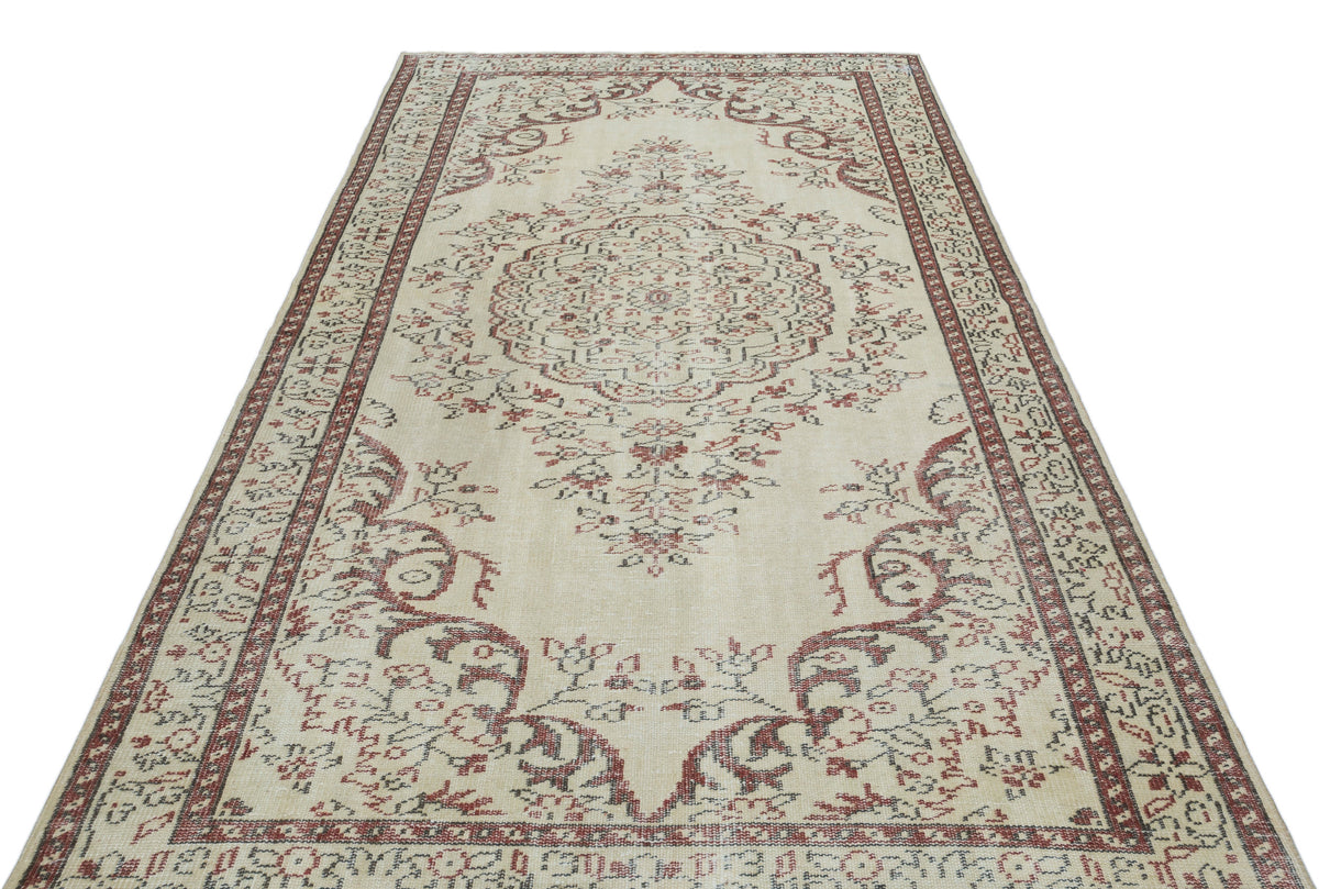 Beige area rug with a central red and charcoal floral medallion and a decorative border on a white background.