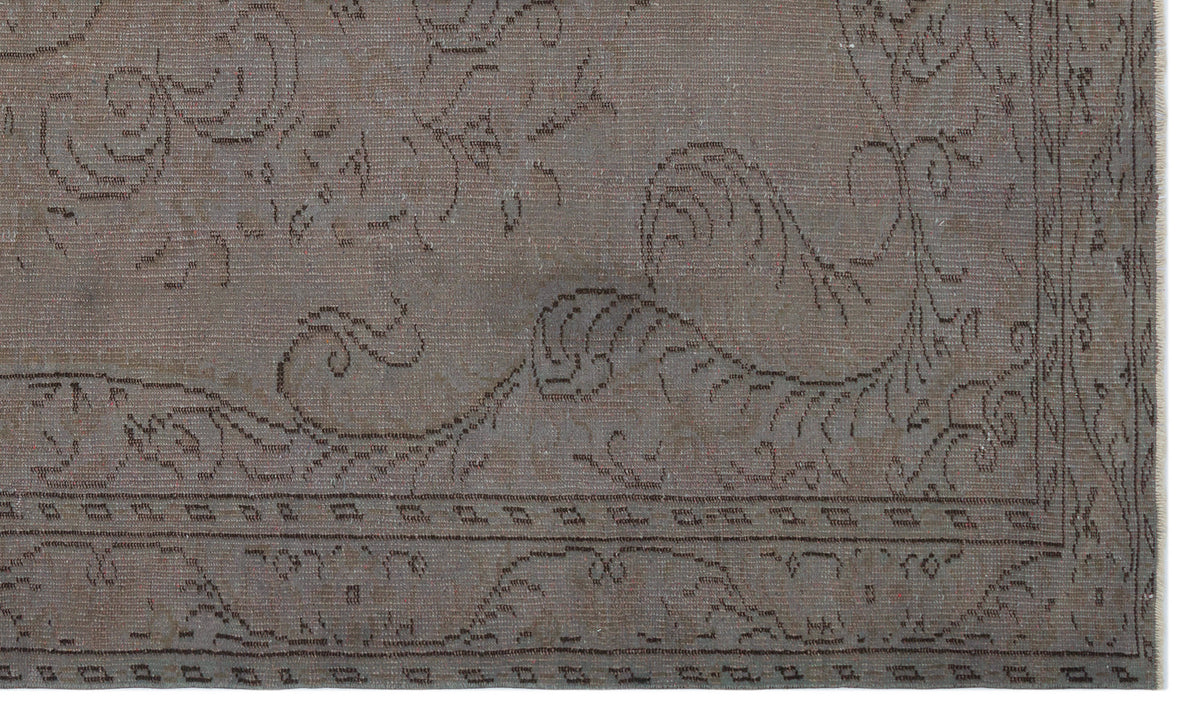 Taupe distressed rug with a faint, dark brown traditional floral medallion pattern and a bordered edge.