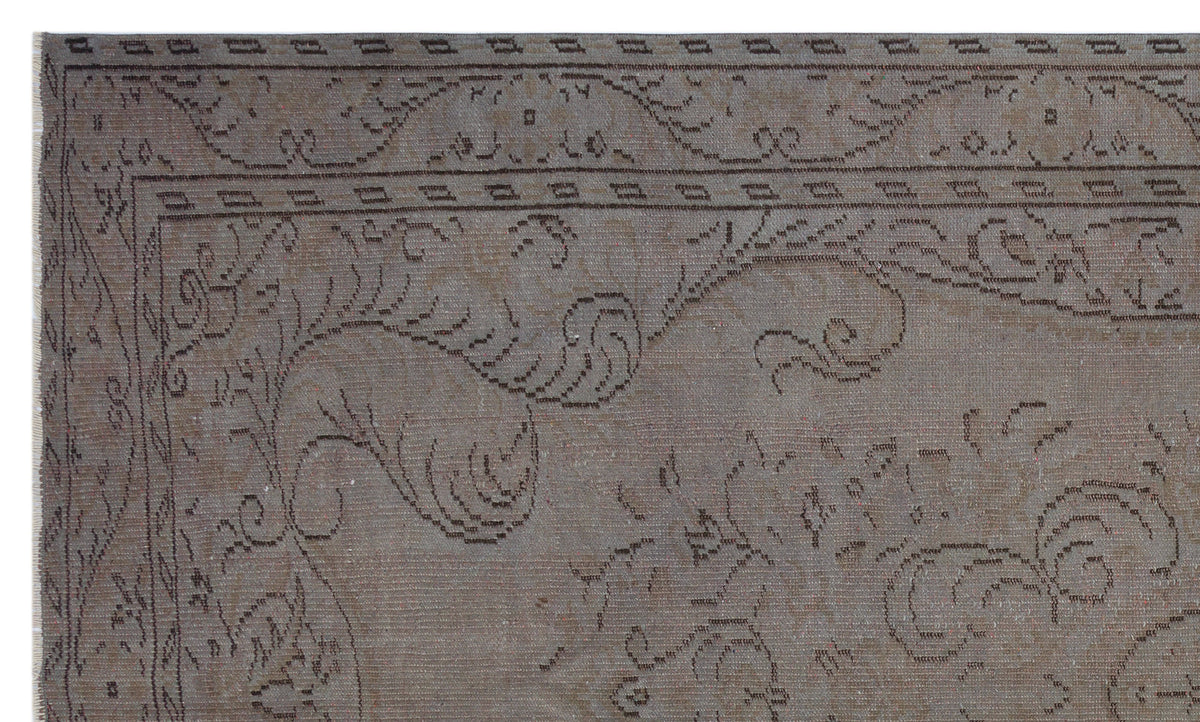 Taupe vintage-style rug with a dark brown linear floral motif and a geometric border.