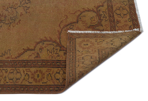Load image 1 in gallery view. Brown and rust-colored vintage rug with a traditional floral border and a folded corner showing white fringe.
