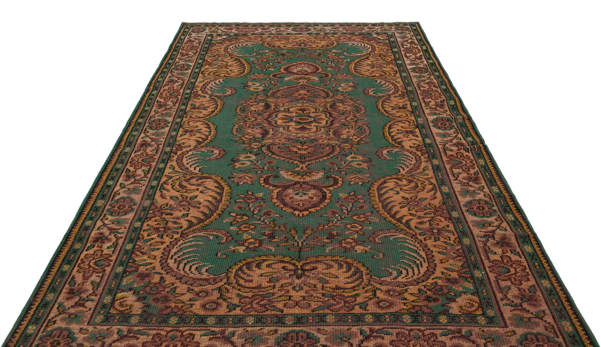 Green and brown traditional rug with a central floral medallion and ornate border pattern on a white background.