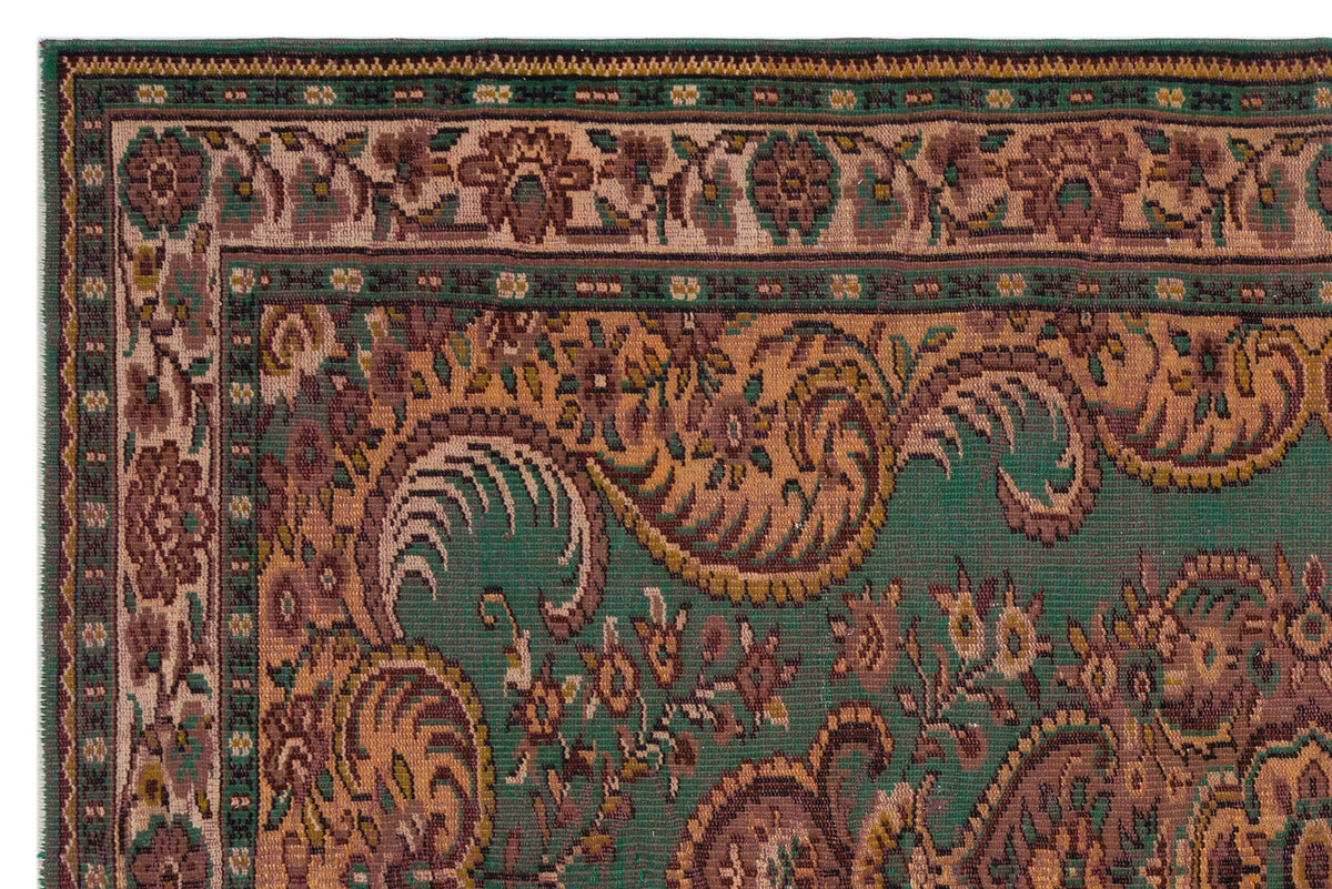 Green and brown traditional rug with a detailed floral and paisley border pattern.