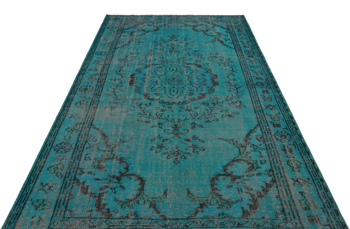 Distressed teal and charcoal vintage-style rug with a central floral medallion and ornate border on a white background.