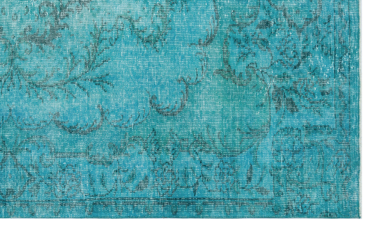 Turquoise rug with a distressed, faded floral medallion pattern and a visible border.