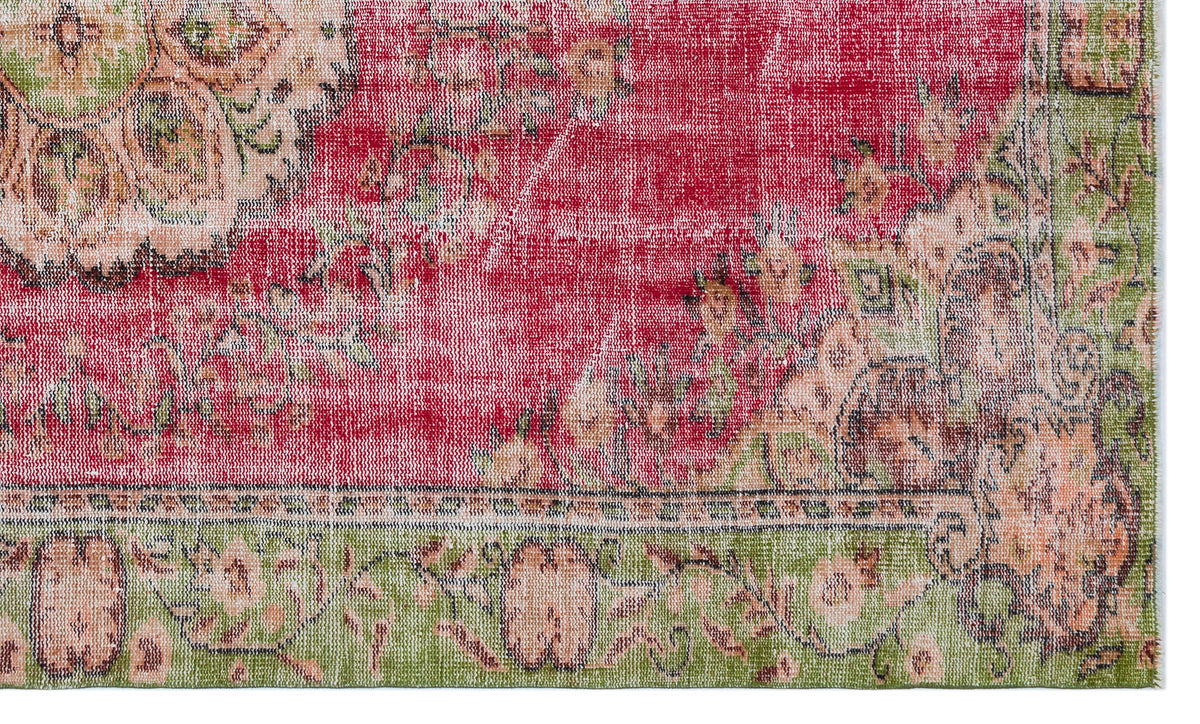 Distressed red and green vintage-style rug with a faded floral medallion pattern and a decorative border.