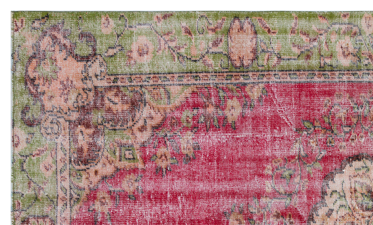 Distressed vintage-style rug with a red central field, green border, and faded floral medallion pattern.