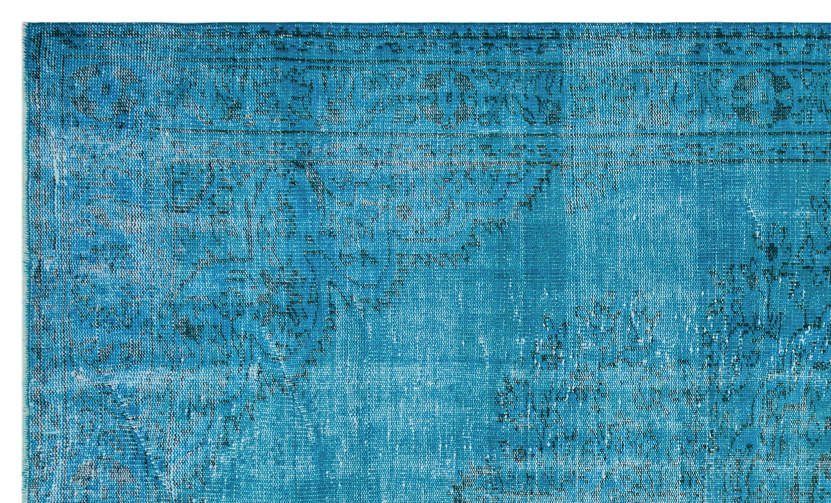 Bright blue distressed rug with a faded black traditional medallion and border pattern.