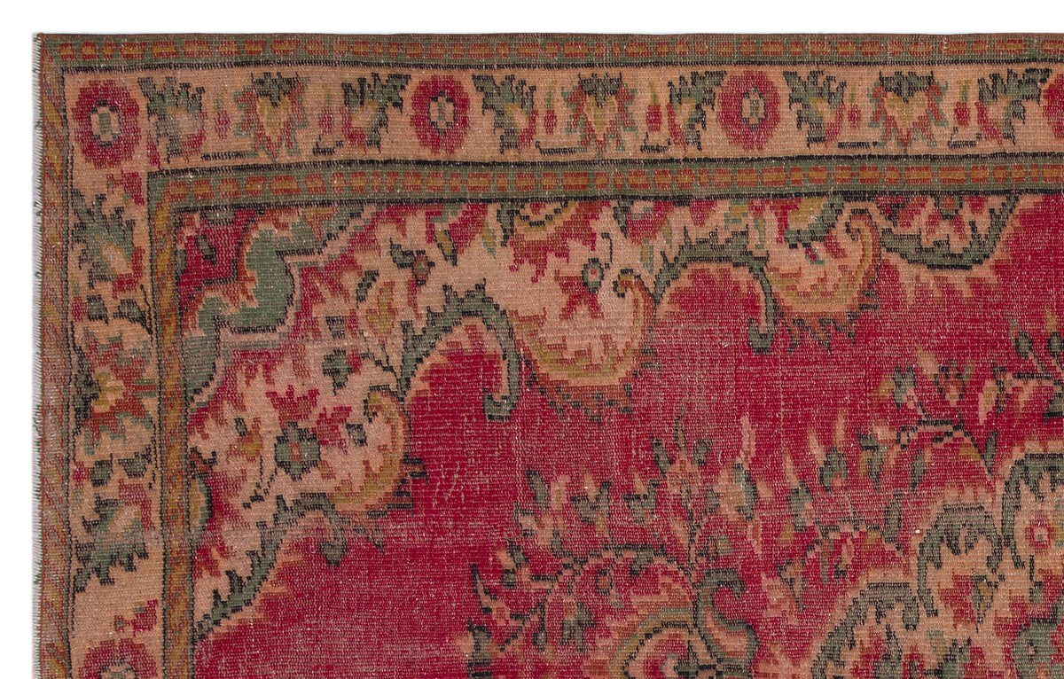 Traditional red rug with a distressed floral border and central medallion pattern in muted green and beige tones.