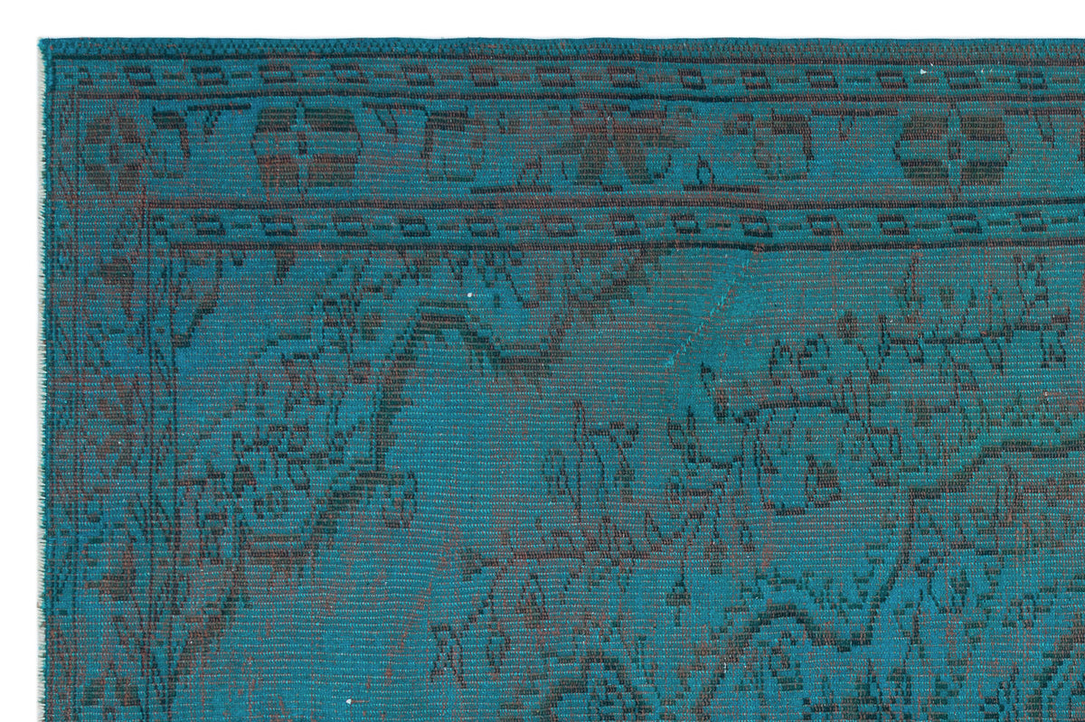 Teal and dark brown rug with a distressed traditional floral medallion pattern and a geometric border.