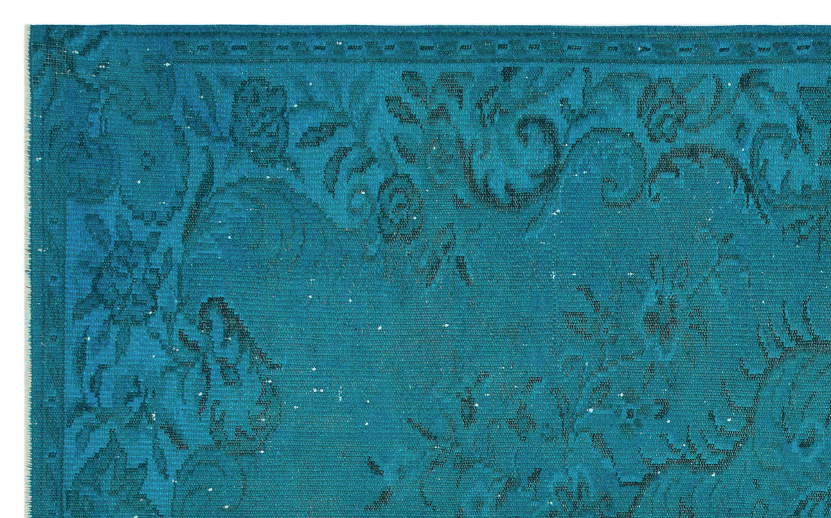 Teal rug with a dark blue distressed floral pattern and a decorative border.