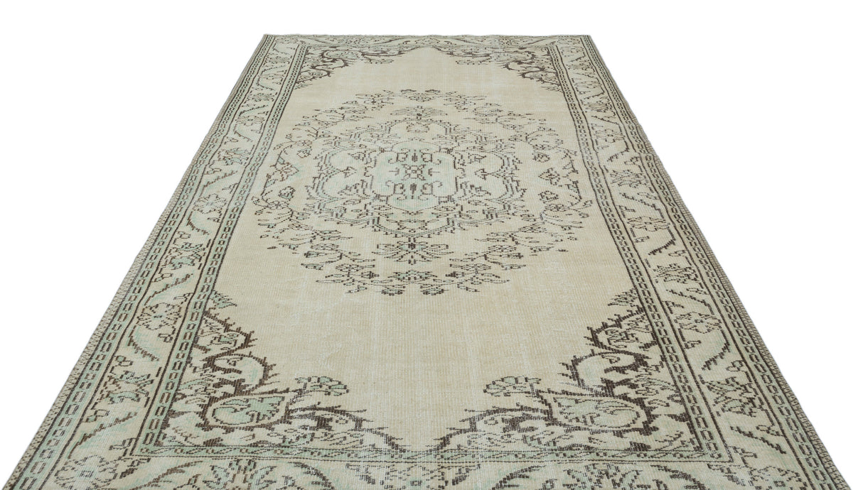 Beige and charcoal distressed traditional rug with a central floral medallion and ornate border pattern.