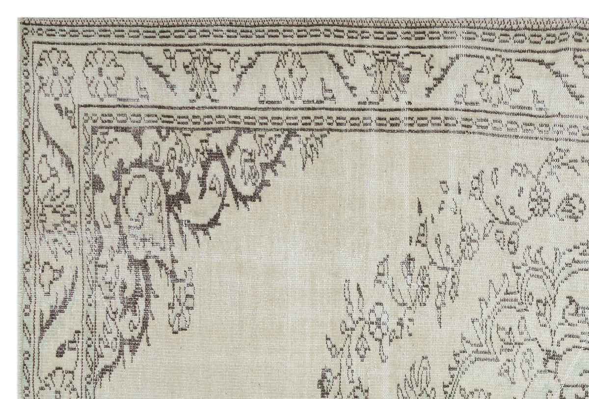 Beige rug with a dark brown distressed floral medallion pattern and a decorative geometric border.