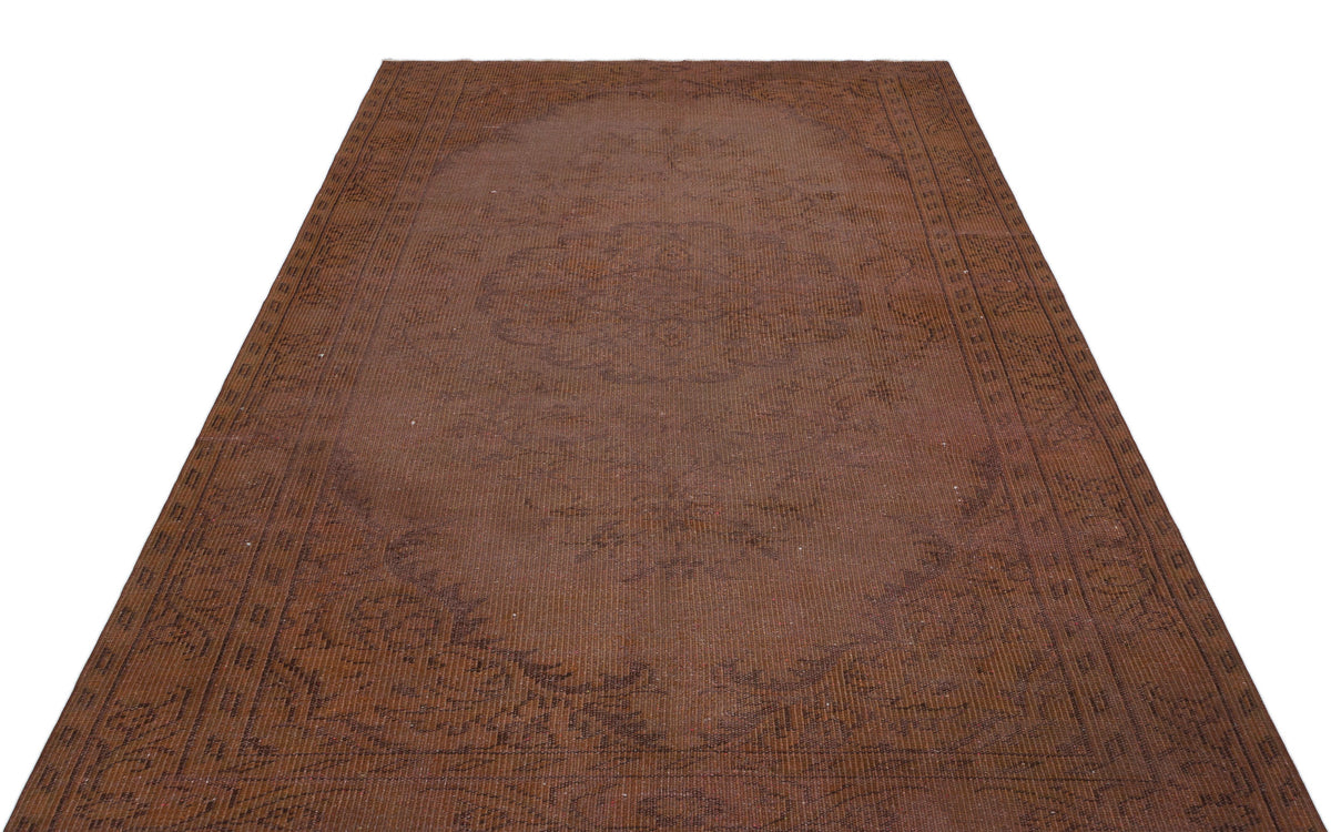 Monochromatic brown rug with a faint, traditional central medallion and ornate border pattern on a white background.
