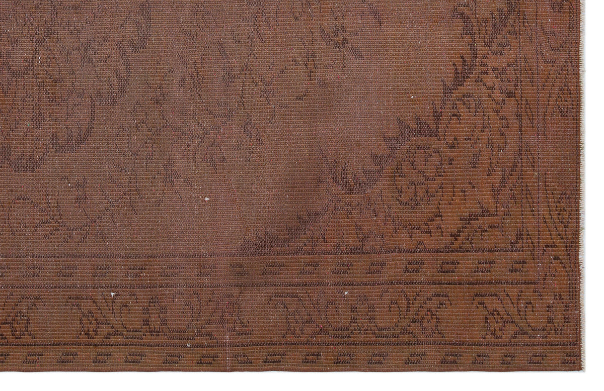 Monochromatic brown rug with a subtle, low-contrast floral medallion pattern and a decorative border.