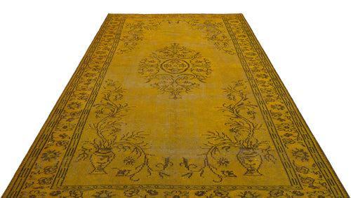 Load image 1 in gallery view. Mustard yellow vintage-style rug with a dark brown central medallion and floral urn border pattern on a white background.