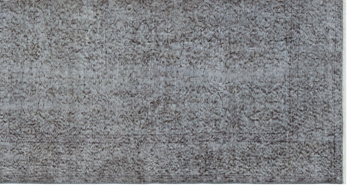 Grey and charcoal distressed rug with a faded traditional floral pattern on a white background.