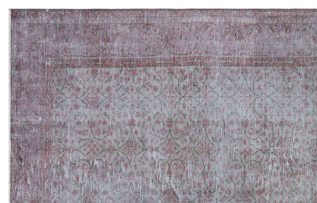 Distressed mauve and grey rug with a faded traditional floral medallion pattern.