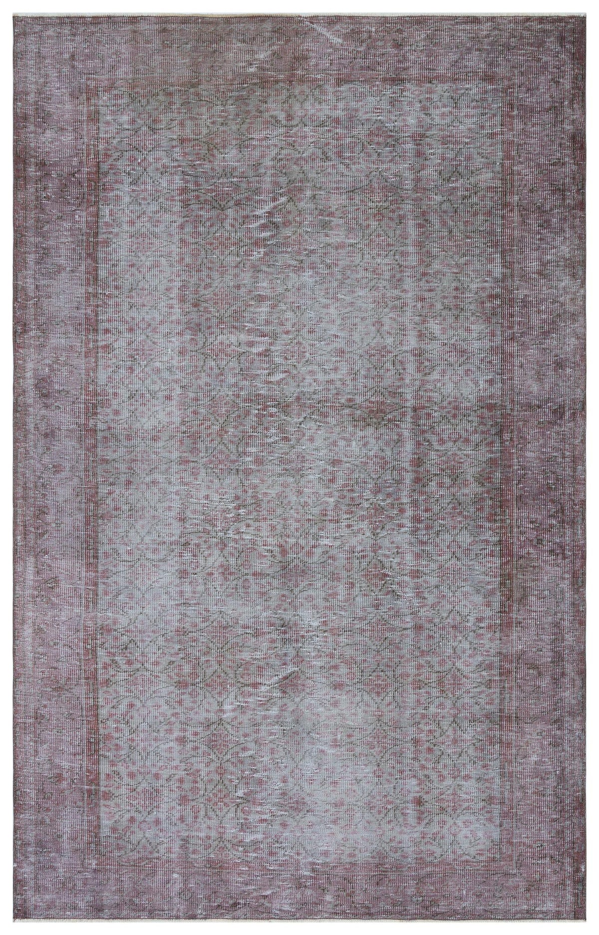 Muted mauve and grey distressed rug with a faded floral medallion pattern and a wide border.