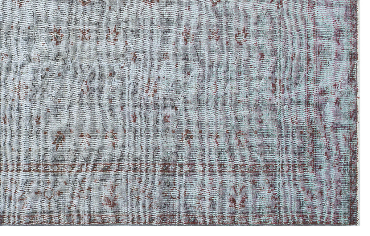 Distressed light gray rug with a faded rust-colored floral medallion pattern and a bordered edge.