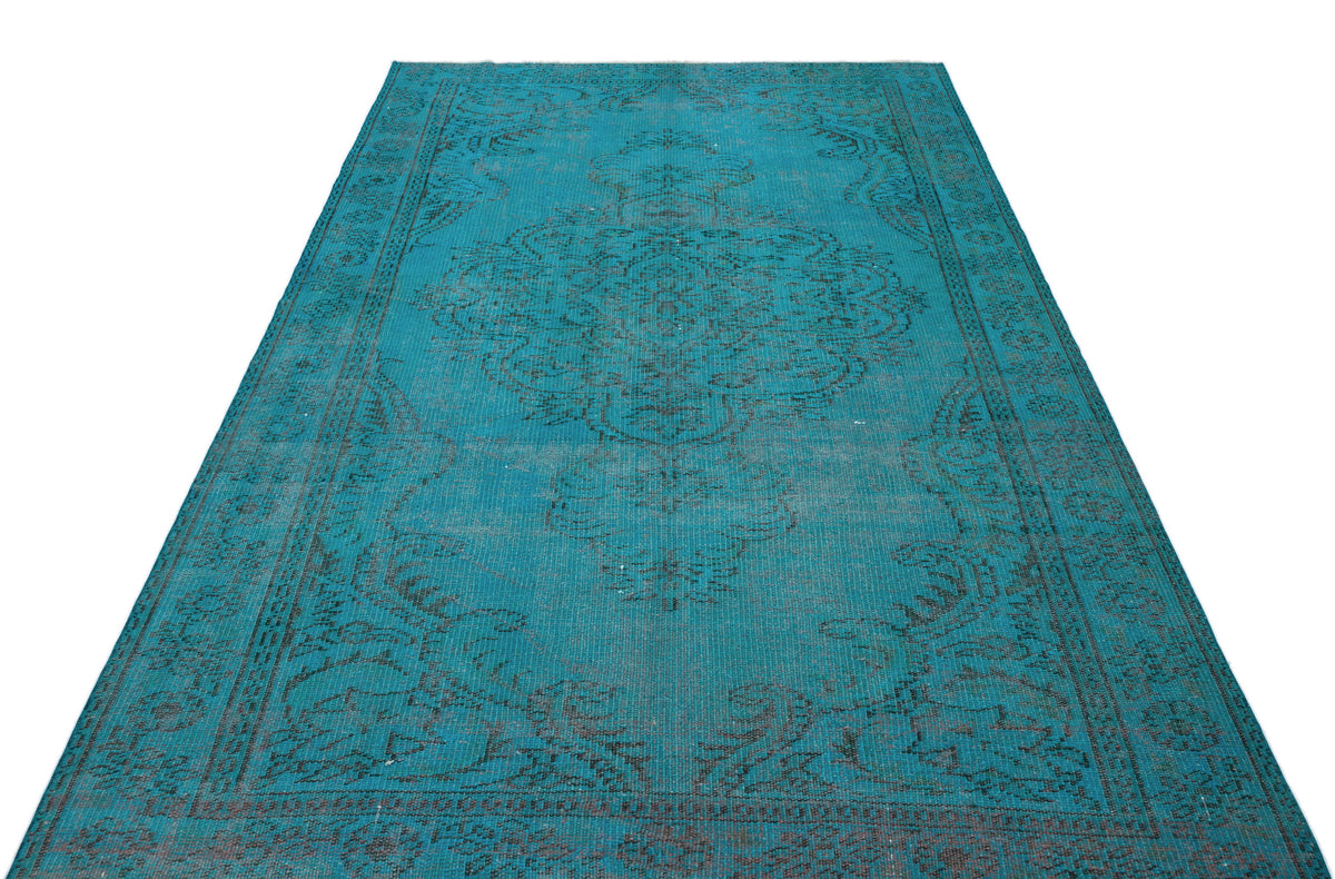 Teal vintage-style rug with a distressed black central medallion and ornate border on a white background.