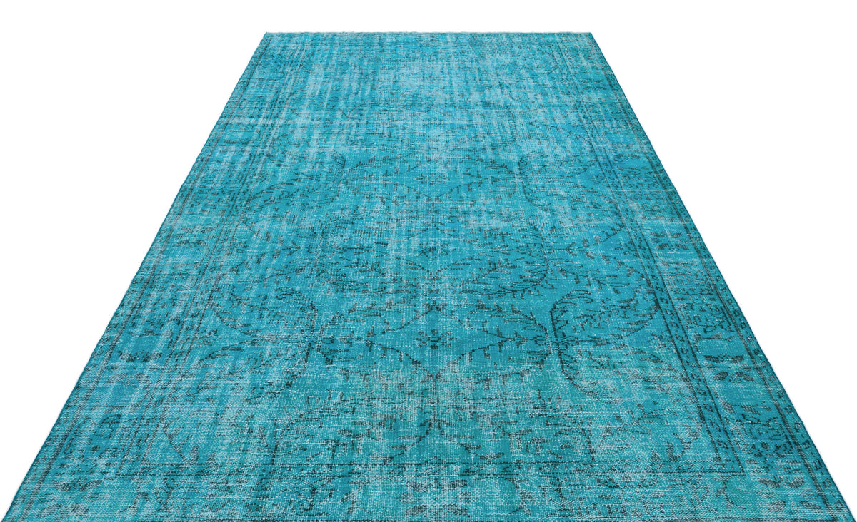 Bright turquoise area rug with a distressed, faded traditional medallion pattern on a white background.