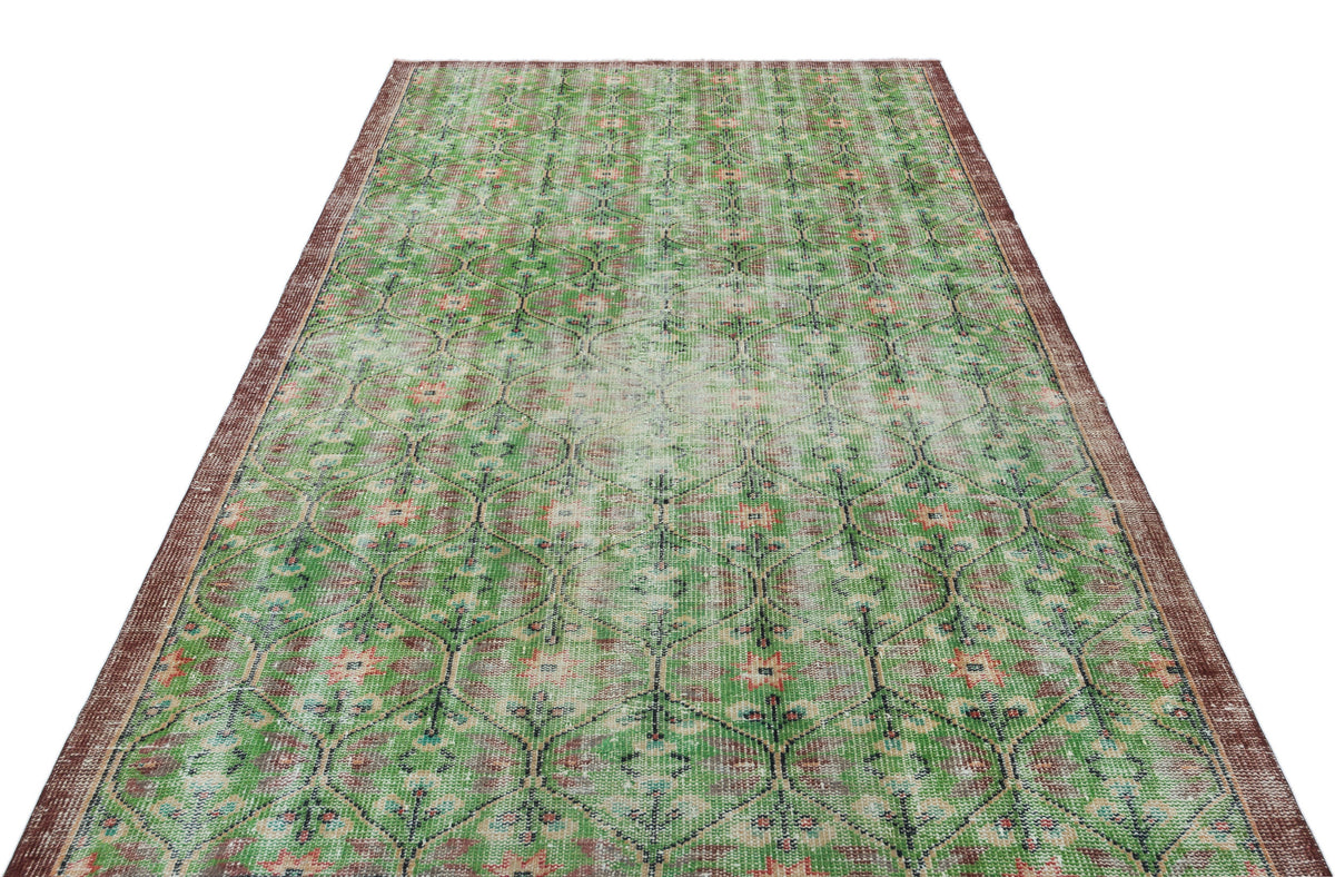 Distressed green and brown vintage-style rug with a repeating geometric floral pattern and a dark border.
