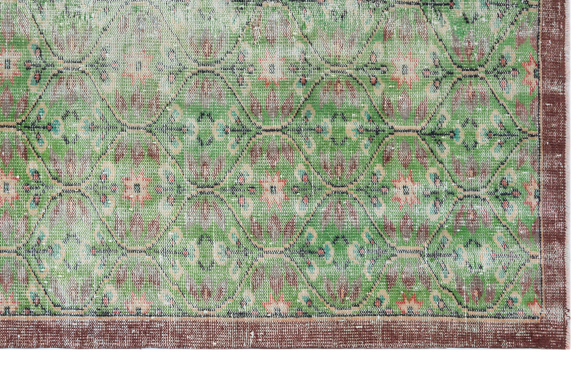 Distressed green rug with a repeating geometric diamond pattern, floral motifs, and a solid brown border.
