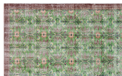 Load image 1 in gallery view. Green and brown distressed rug with a repeating geometric diamond pattern and floral motifs.