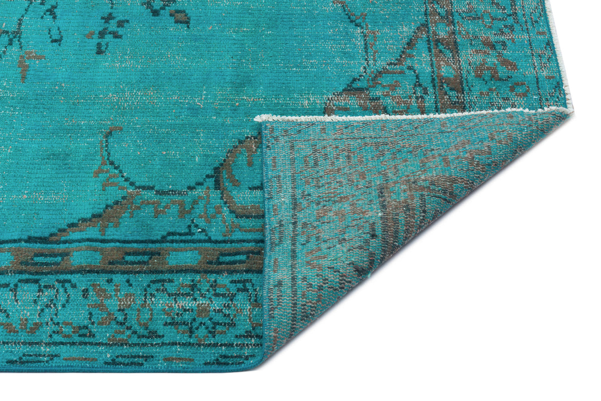 Teal and grey distressed traditional rug with a folded corner showing the underside texture.