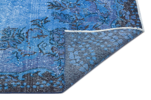 Load image 1 in gallery view. Blue and dark grey distressed floral medallion rug with a folded corner showing the woven backing.