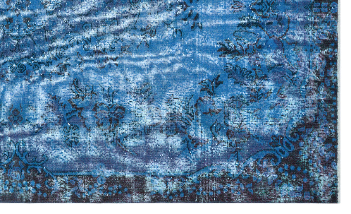Blue and black distressed rug with a faded floral medallion pattern on a white background.